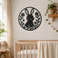 A black metal wall art piece featuring a bunny and floral design, displayed on a beige wall above a wooden crib in a softly styled nursery.