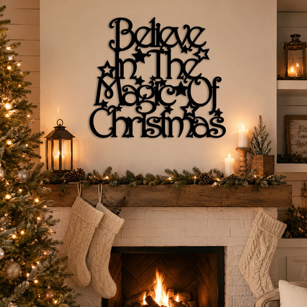 Black metal wall art with the phrase 'Believe in the Magic of Christmas' displayed above a decorated fireplace mantel with stockings, candles, and a Christmas tree.