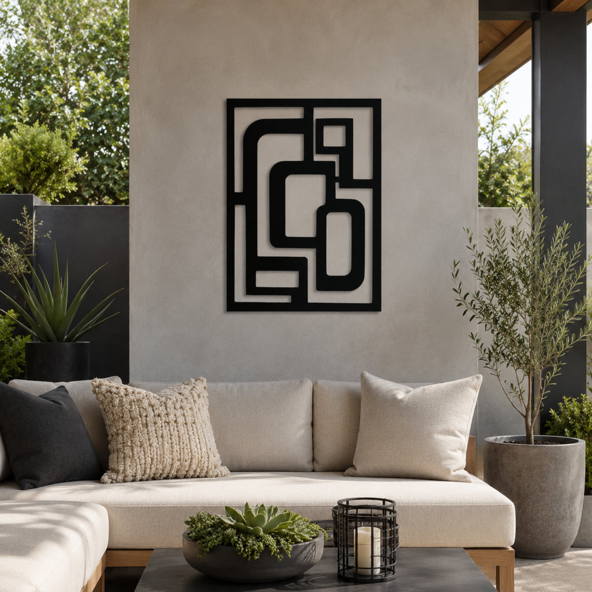 Abstract black metal wall art with a geometric maze-like pattern, displayed on a textured beige wall above a modern outdoor sofa with neutral-toned cushions.