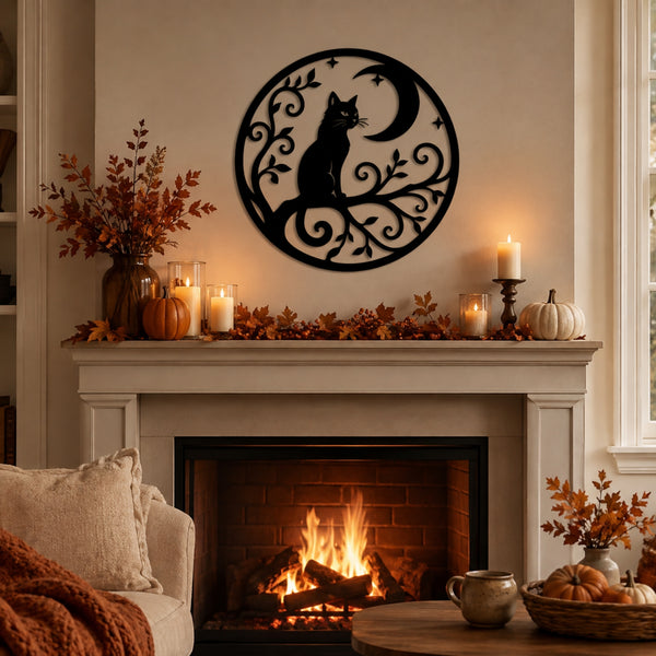 A black metal wall art piece featuring a cat silhouette on a crescent moon with decorative scrollwork, displayed above a fireplace in a cozy living room setting with fall decorations.