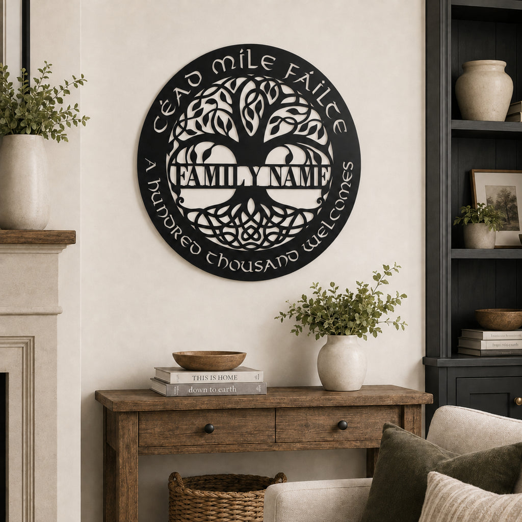 A circular black metal wall sign featuring a white tree of life design and the text 'CEAD MILE FÁILTE' and 'FAMILY NAME' and 'A hundred thousand welcomes' in Irish, displayed on a beige wall above a wooden console table in a styled living room setting.