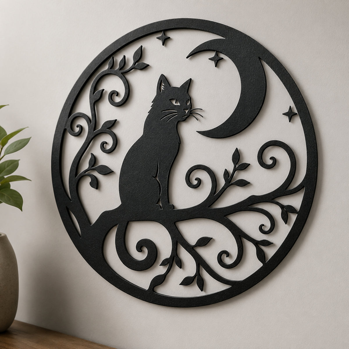 Black metal wall art featuring a cat silhouette perched on a branch with a crescent moon and stars, displayed against a light beige wall with a small plant in the foreground.