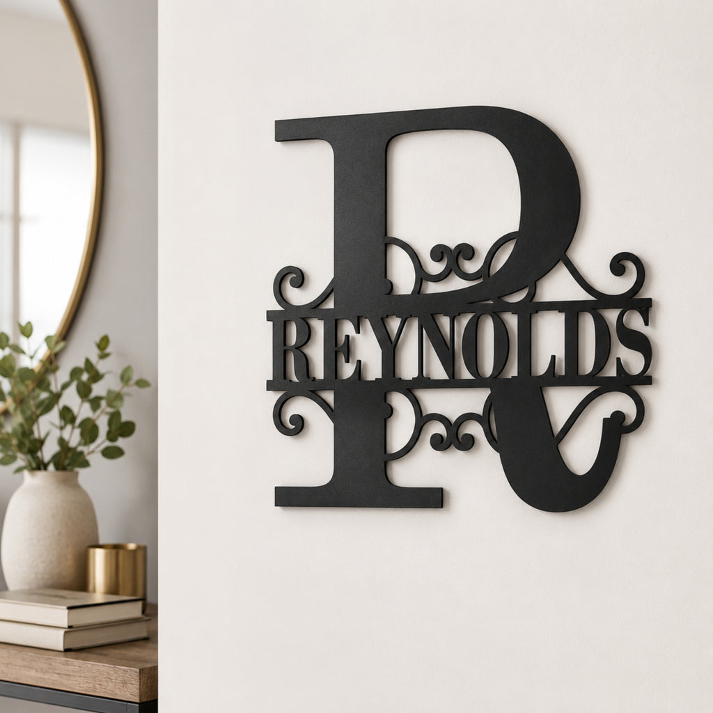 A black metal wall sign featuring a large decorative letter R with the name 'REYNOLDS' across the center, mounted on a white wall in a styled interior setting.