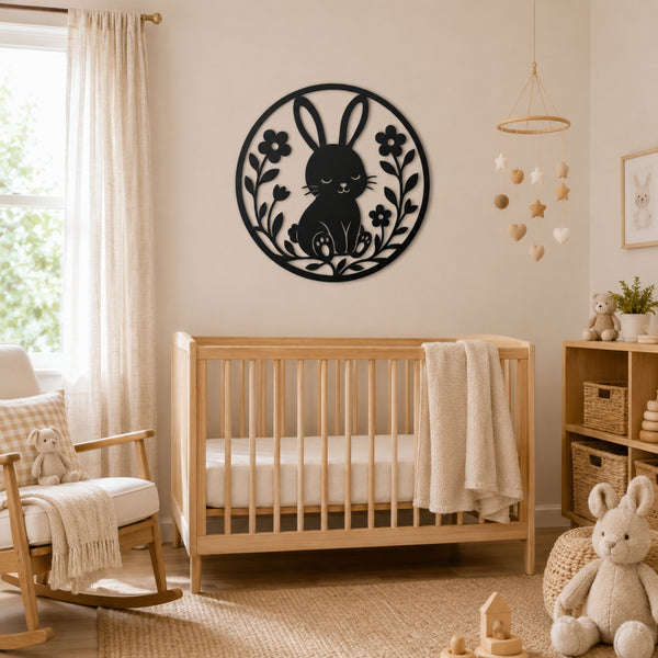 A black metal wall art piece featuring a bunny and floral design, displayed in a styled nursery above a wooden crib.