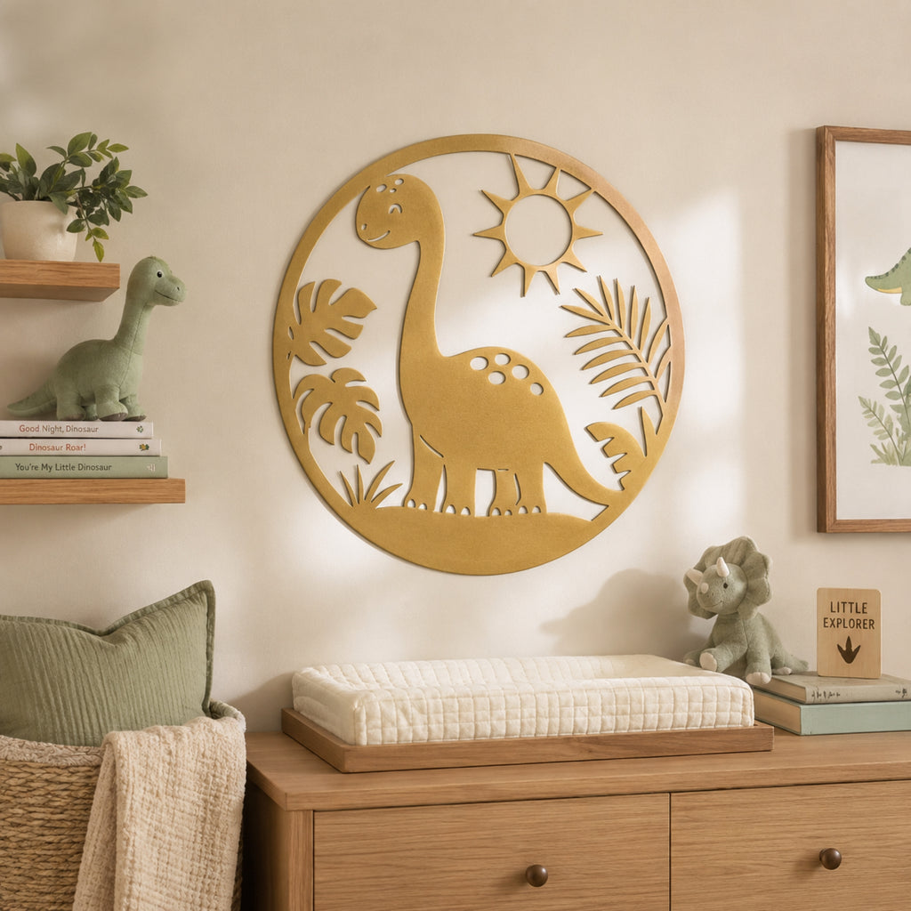 A round metal wall art piece featuring a dinosaur silhouette with a sun and palm leaves, displayed on a beige wall in a styled nursery setting above a changing table.