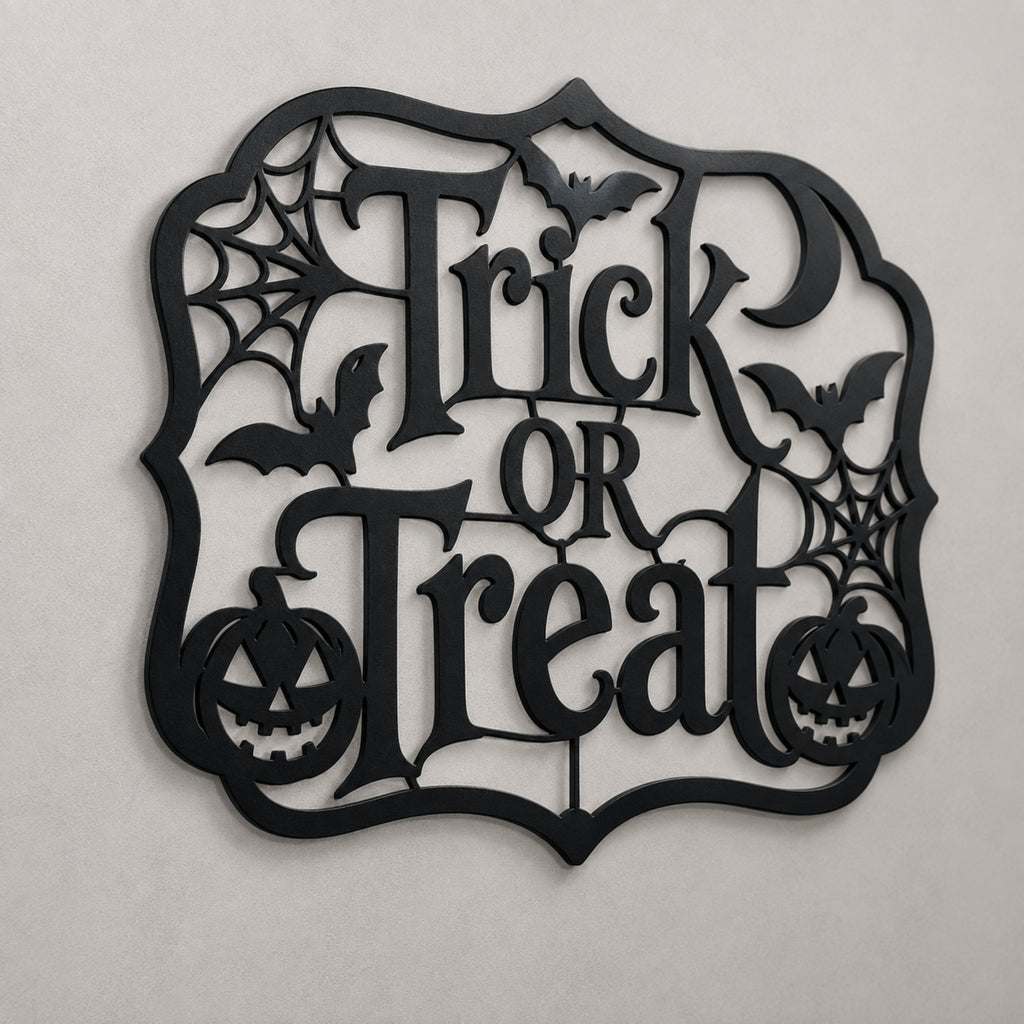 Black metal Halloween wall decor sign featuring the words 'Trick or Treat' in an ornate cutout font, surrounded by bats, spiderwebs, and jack-o'-lanterns, shown against a neutral light gray background.