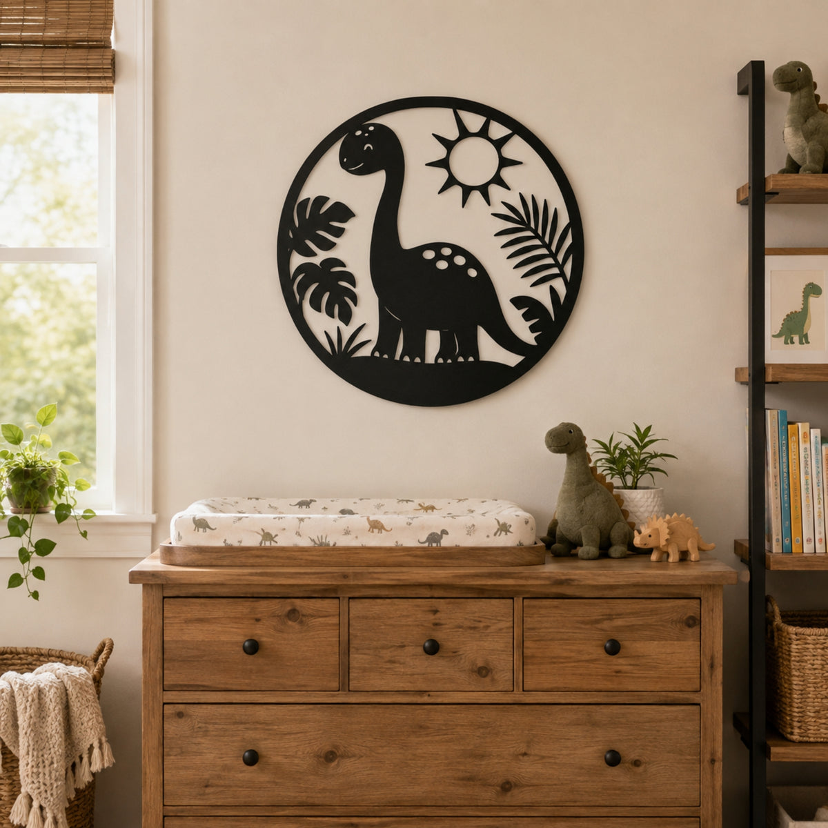 A black circular metal wall art piece featuring a dinosaur silhouette, sun, and palm leaves, displayed on a beige wall above a wooden dresser in a styled nursery setting. Main image