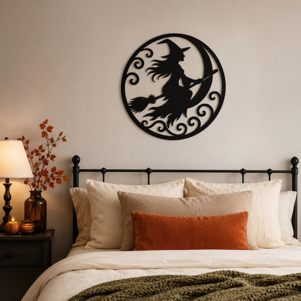 Black metal wall art featuring a witch riding a crescent moon, displayed above a bed in a cozy bedroom setting.