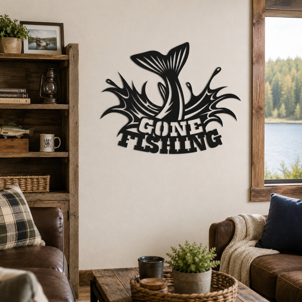 A black metal wall art piece featuring a jumping fish and the words 'GONE FISHING' is mounted on a beige wall in a rustic living room setting with a wooden bookshelf, leather sofa, and window overlooking a lake.