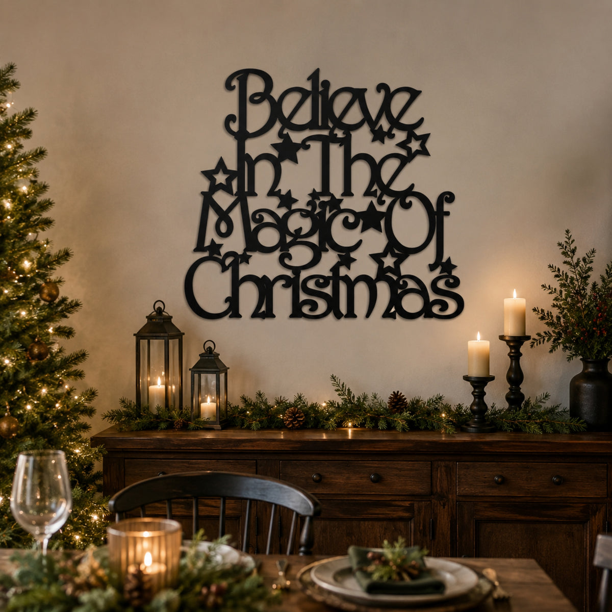Black metal wall art with the phrase 'Believe in the Magic of Christmas' styled on a beige wall above a decorated holiday table with candles, pine garland, and a Christmas tree.
