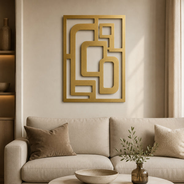 Gold geometric wall art with an abstract maze-like frame design, displayed on a beige wall above a modern light beige sofa in a styled living room setting.