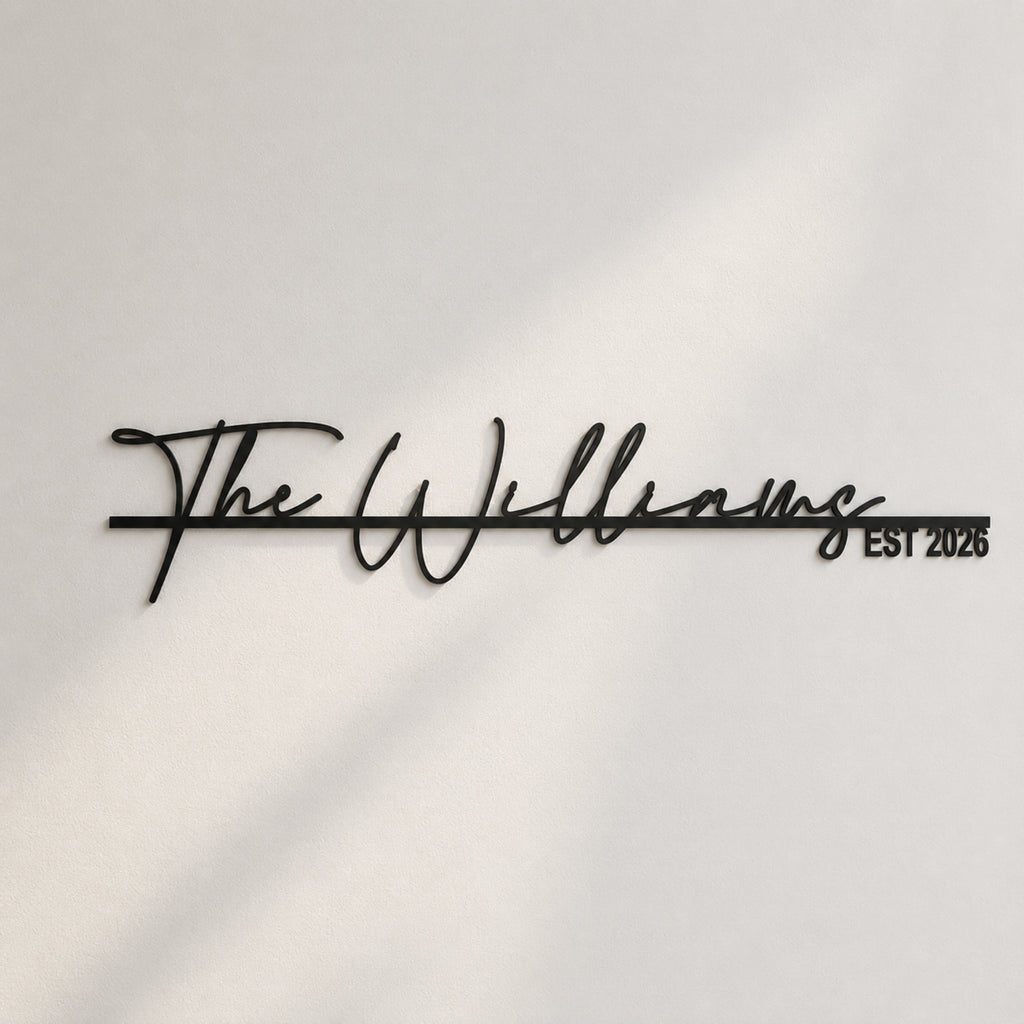 Black metal script wall sign reading 'The Williams EST 2026' mounted on a white wall with soft diagonal shadows.