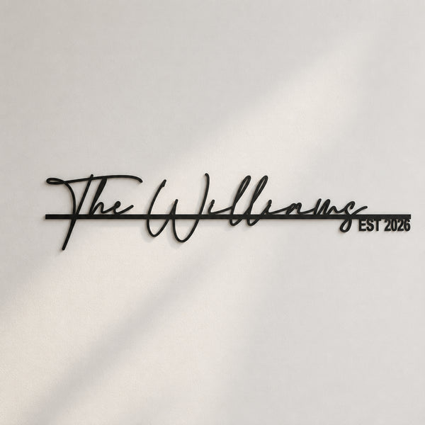 Black metal script wall sign reading 'The Williams EST 2026' mounted on a white wall with soft diagonal shadows.