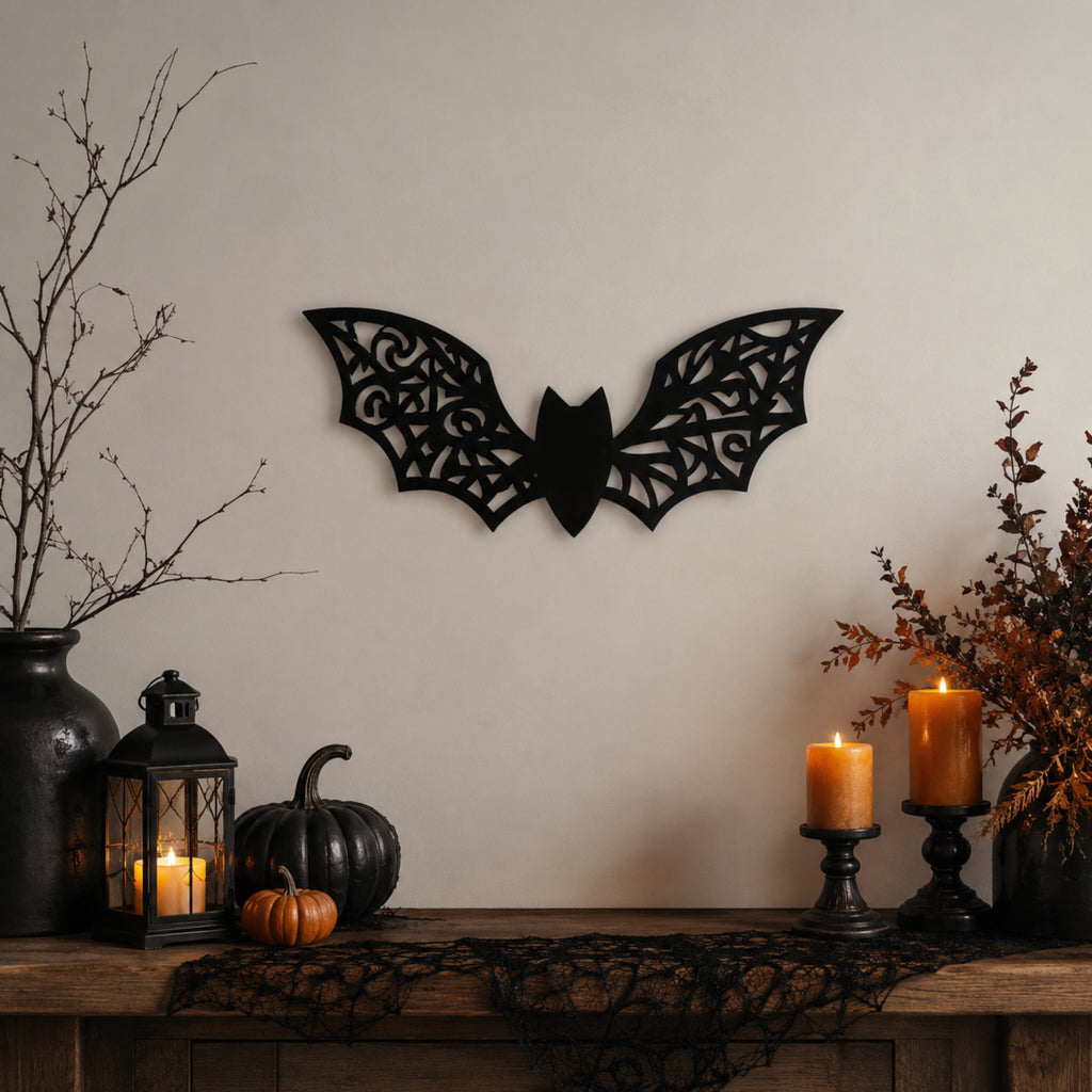 Black metal bat wall decor mounted on a beige wall above a rustic wooden mantel styled with candles, pumpkins, a lantern, and dried branches.