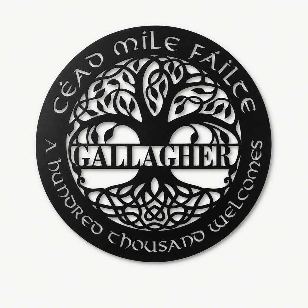A circular black metal wall sign featuring a stylized tree of life with the name 'GALLAGHER' in the center, surrounded by the Irish phrase 'Éad míle féilte' and 'A hundred thousand welcomes' in white cutout lettering, shown on a light off-white background.