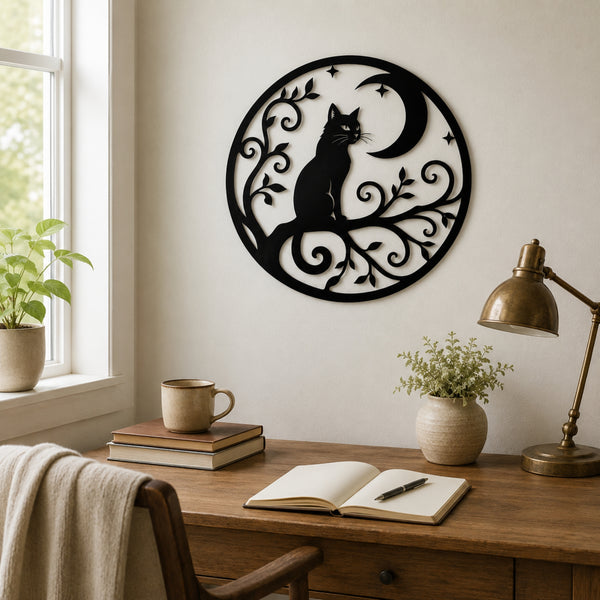 Black metal wall art featuring a cat silhouette sitting under a crescent moon with decorative scrollwork, displayed on a wall above a wooden desk in a styled home office setting.